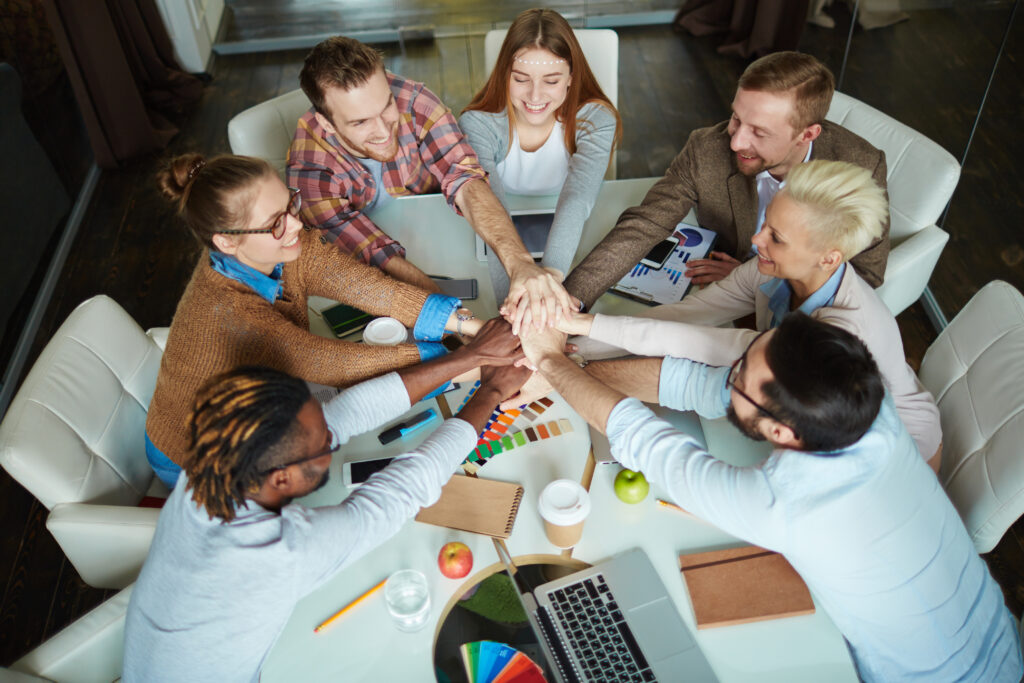 Several managers making pile of hands over workplace